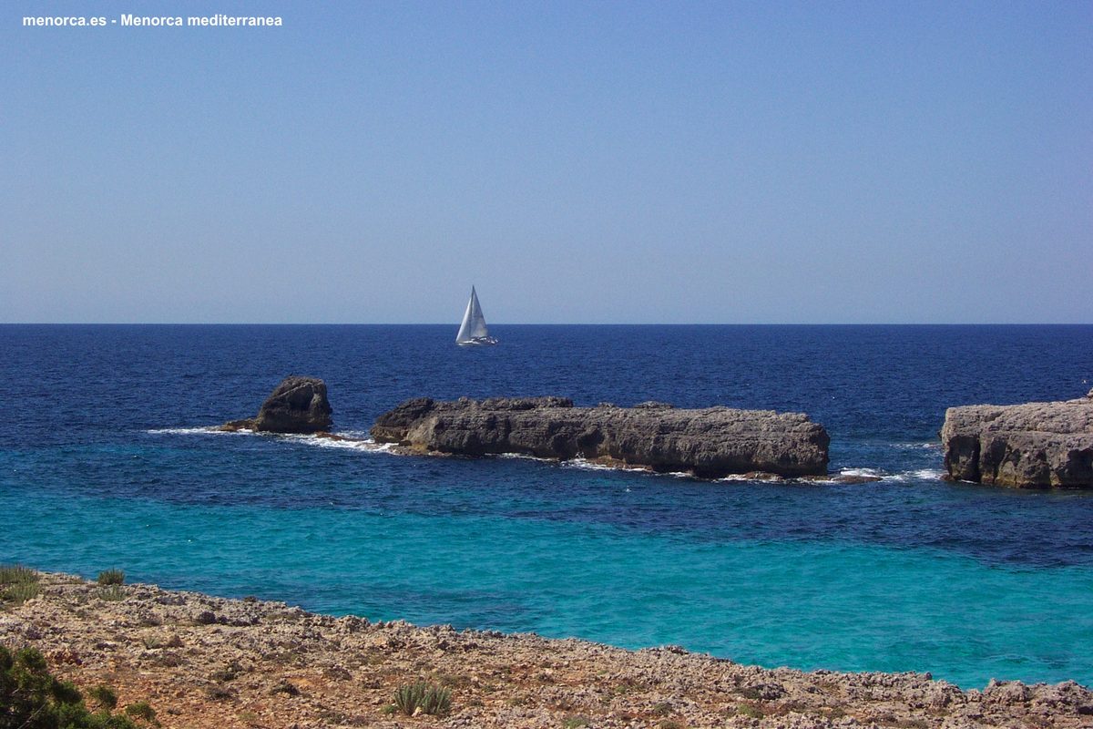 Velero navegando junto a los acantilados de la costa de Menorca