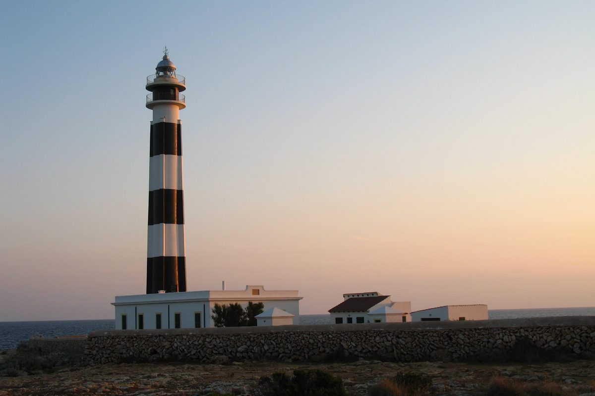 Faro junto al mar al atardecer, en la costa de Menorca