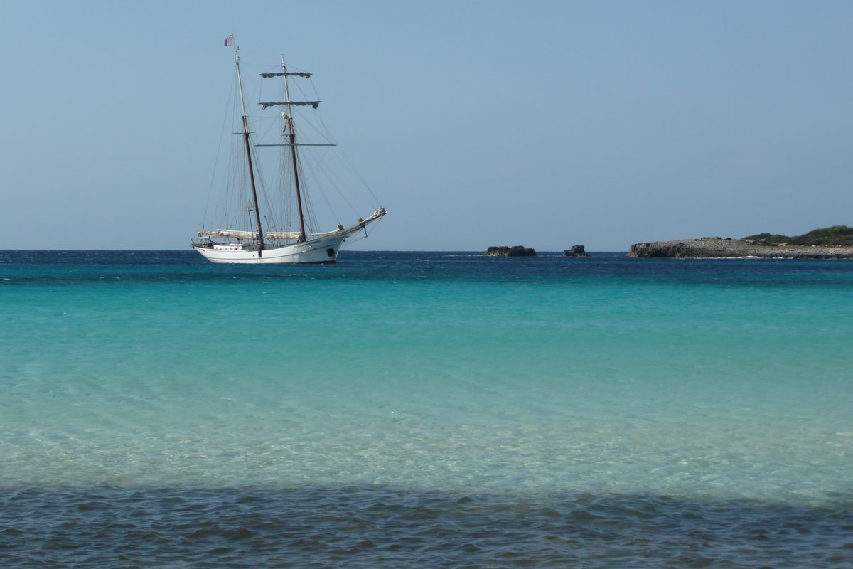 Goleta de vela clásica fondeada en aguas turquesas de Menorca