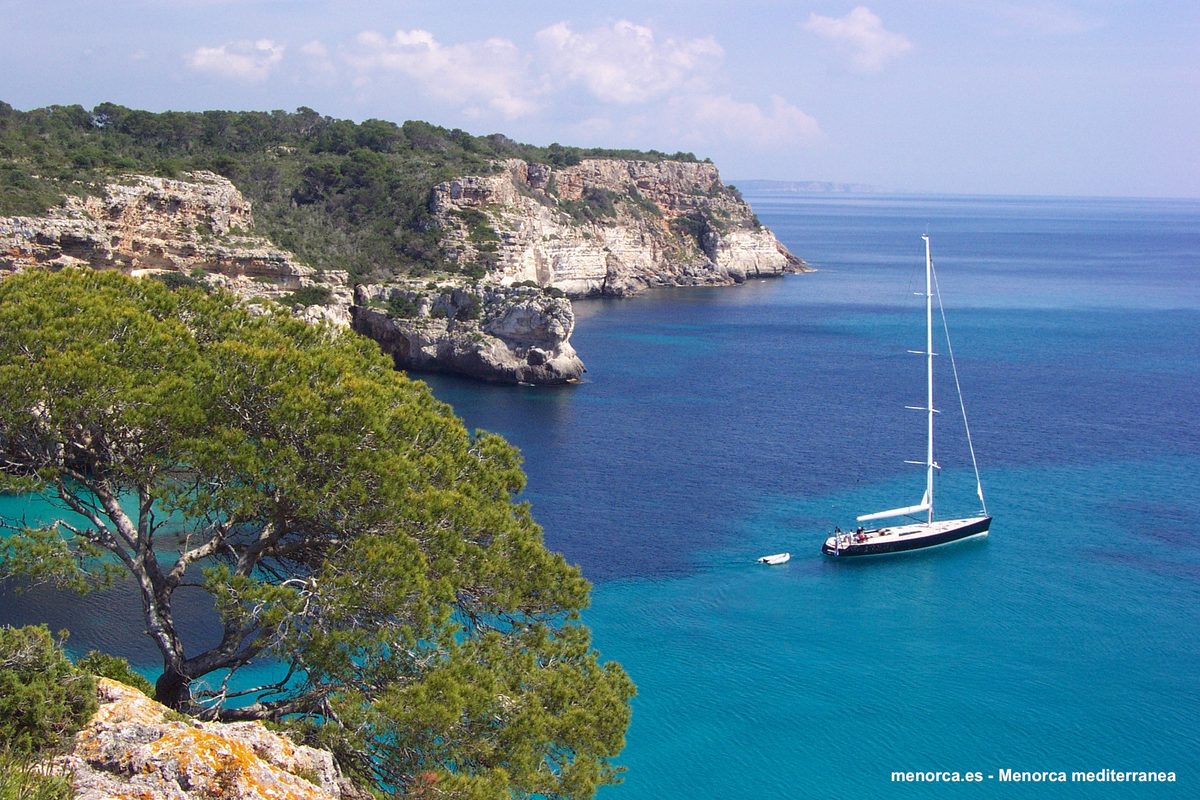 Velero fondeado en una cala de Menorca de agua turquesa